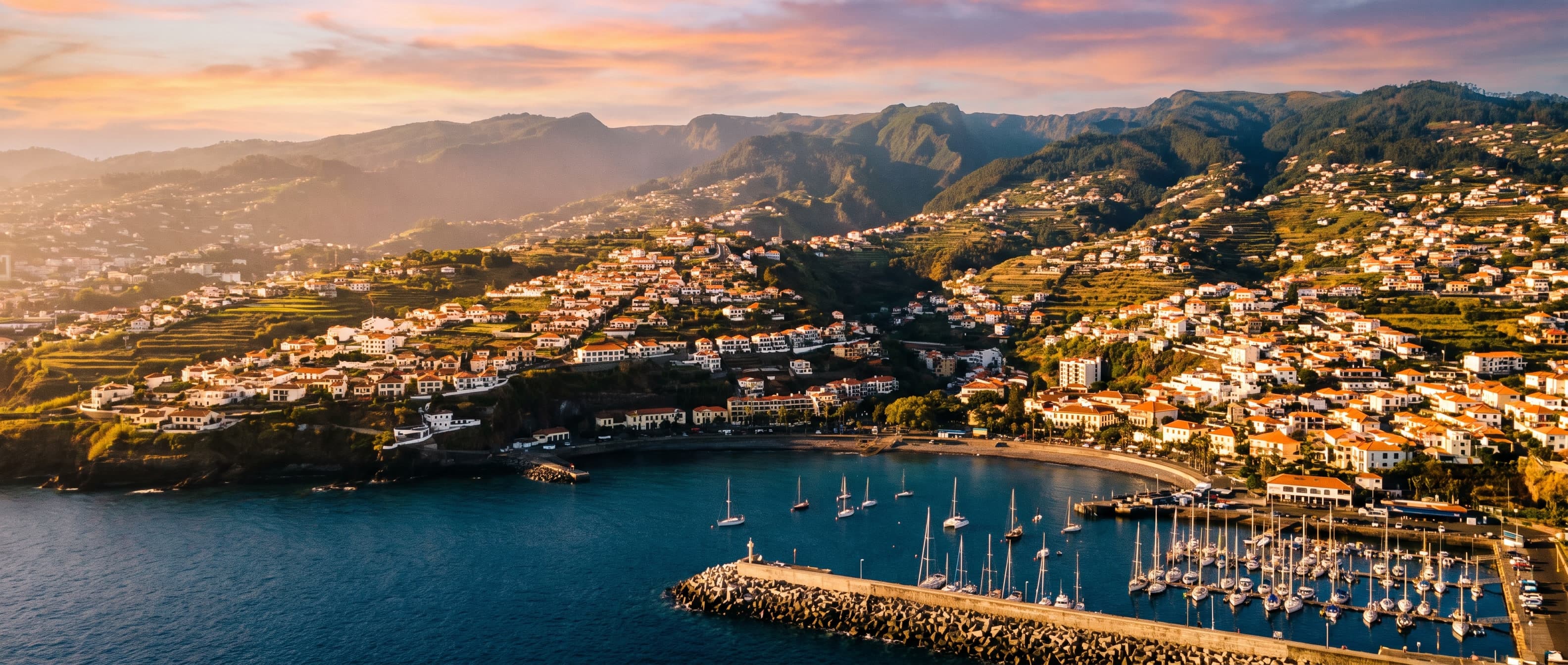 Funchal's amphitheatre of terracotta roofs climbing the hills above the marina at golden hour