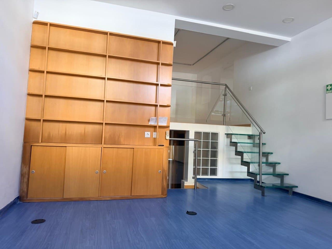 O interior da loja — mezanino, escada de vidro e estantes por medida